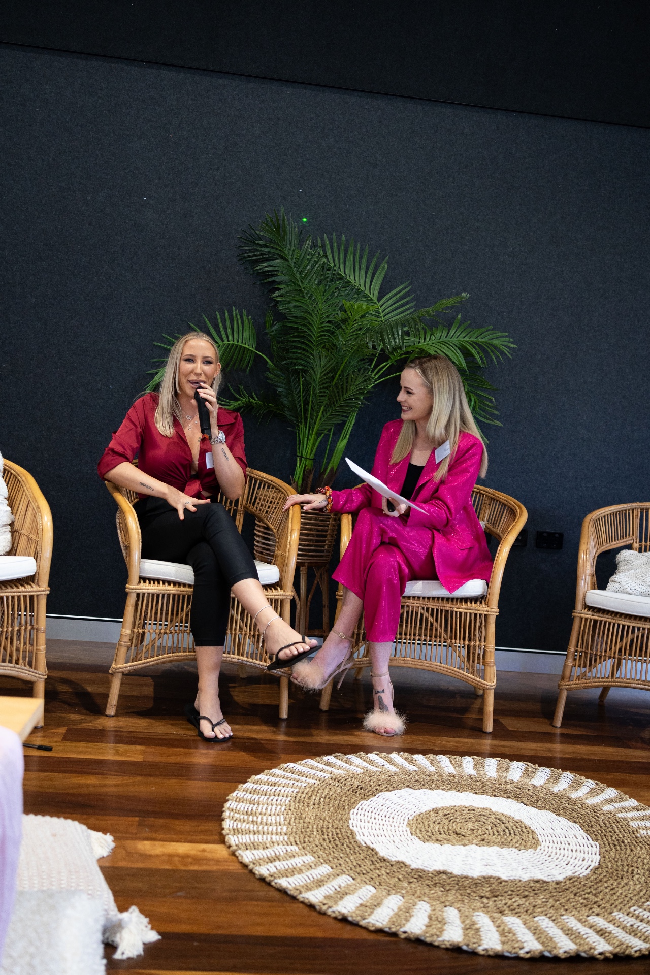 Caitlyn Hudson in a hot pink suit, hosting a panel conversation on stage at a PPP Network event.